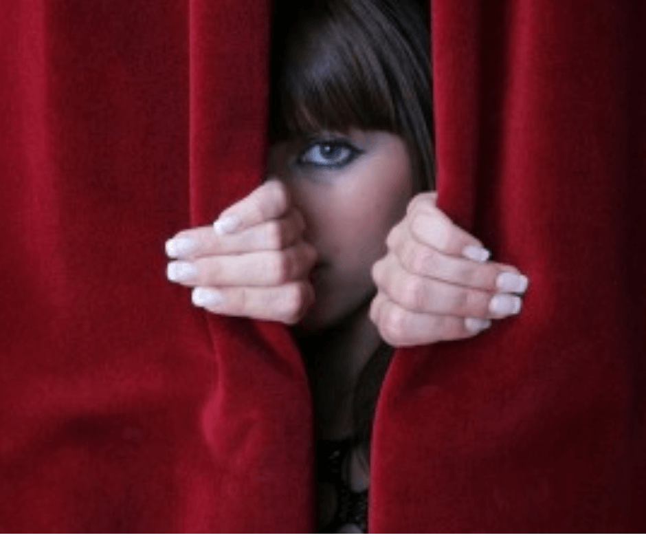 woman pulling back red curtains