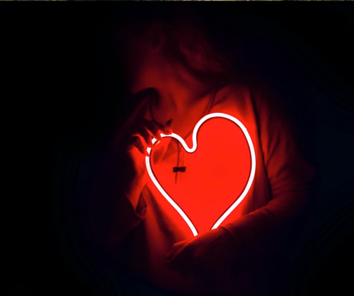 Woman holding glowing red heart