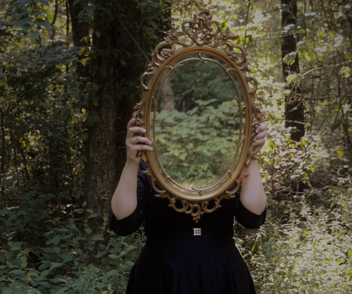 Woman holding mirror in front of her face